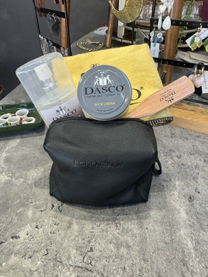 Black leather bag with Dasco shoe cream on a concrete surface